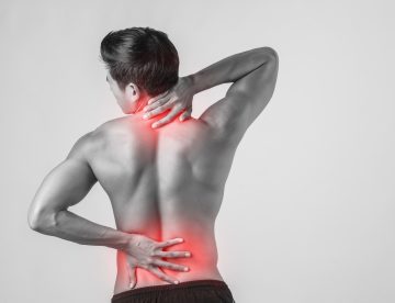 Mujer joven con dolor lumbar que se sujeta la espalda, ejemplo de los riesgos de la artrodesis y la pseudartrosis