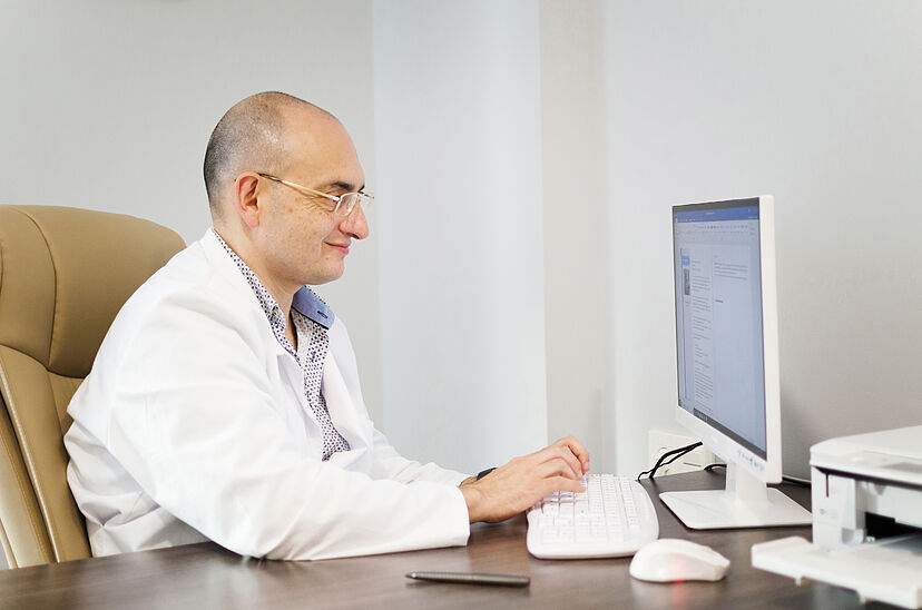 Dr. Bernardo Mosqueira en consulta médica realizando diagnóstico de problemas de columna a un paciente