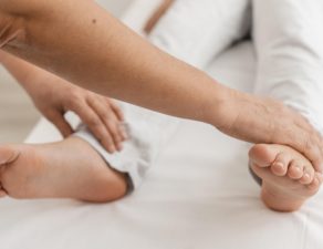 Persona sujetándose el pie por sensación de hormigueo o adormecimiento